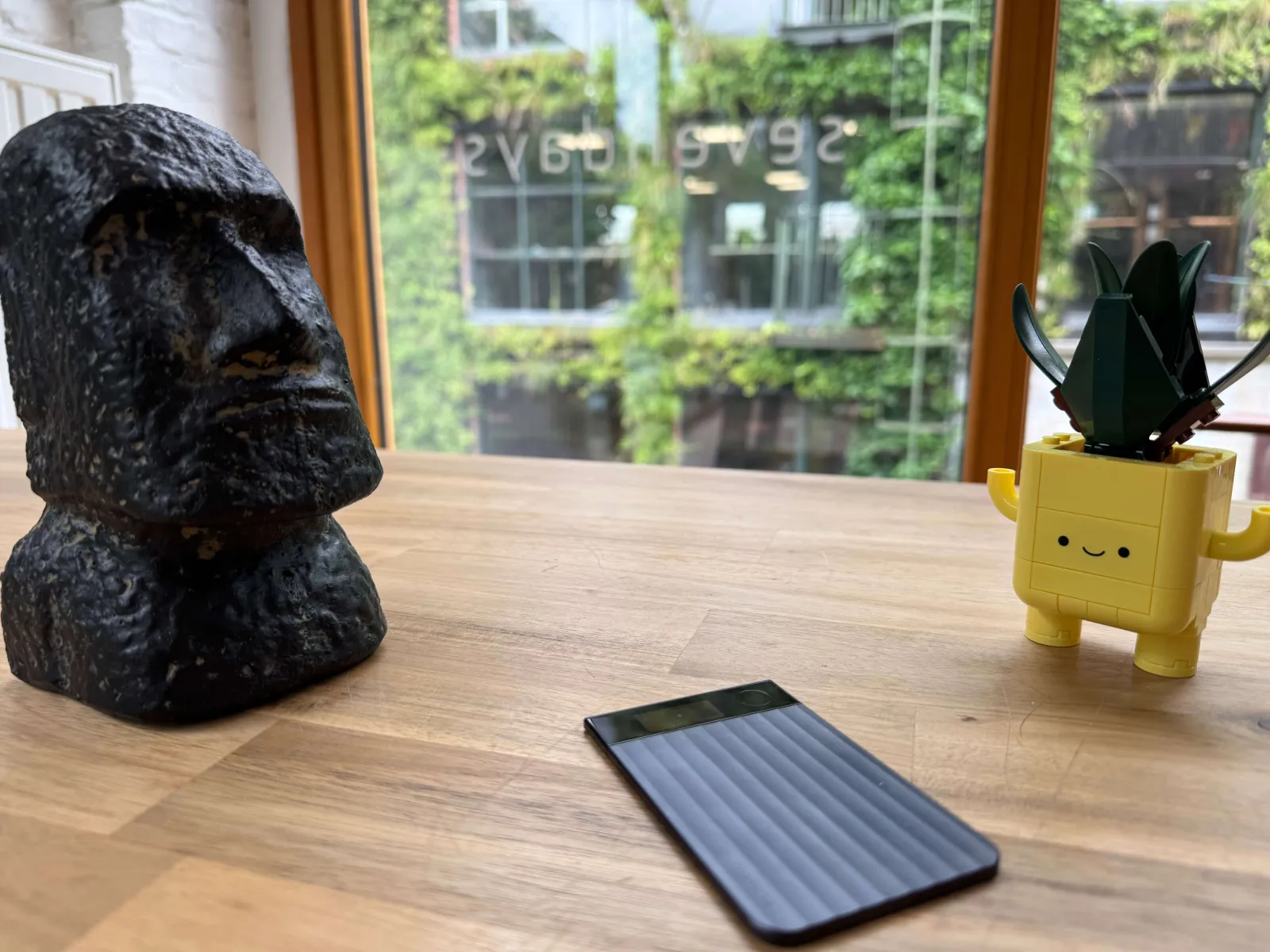 A voice recorder on a meeting table at Sevendays, next to a moai statue and a Lego plant