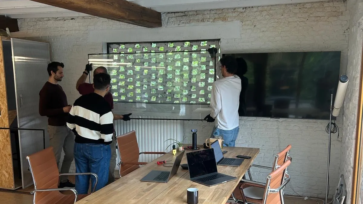 Colleagues fitting a glass wall into an opening at the Sevendays office