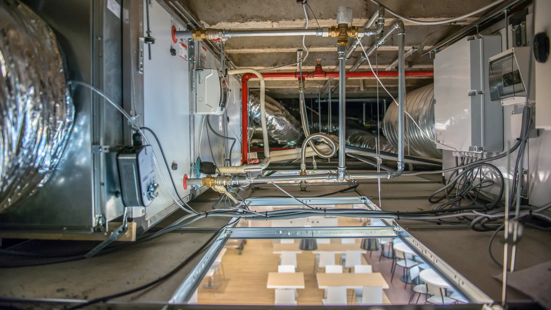 Technische installatie op een werf: leidingwerk en ventilatiekanalen boven een plafond